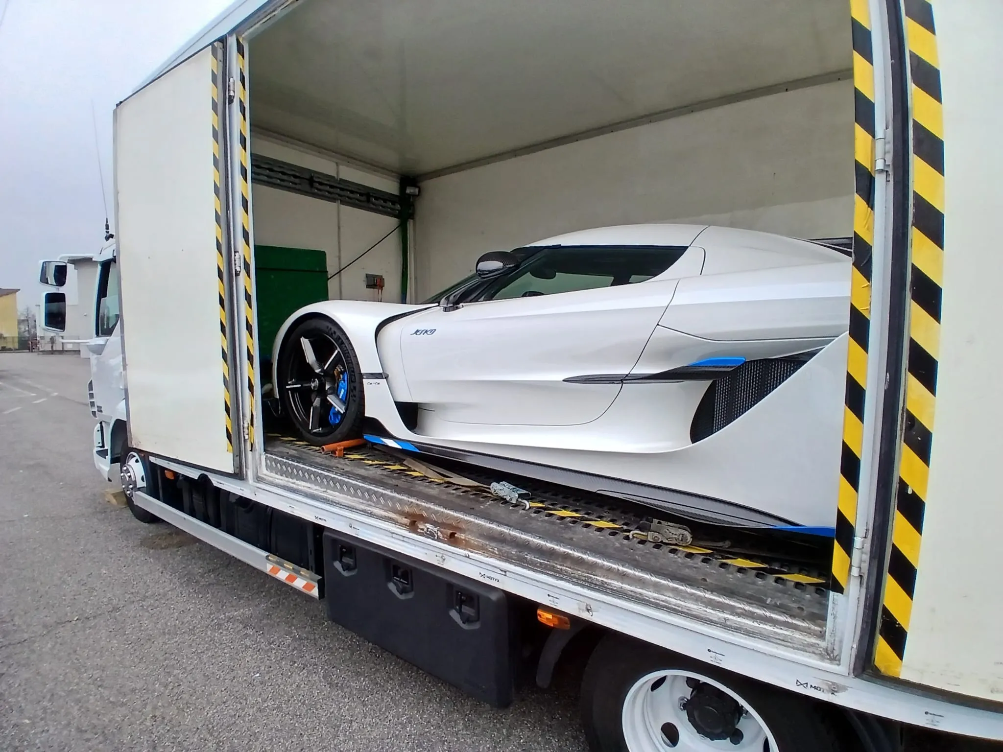 Hypercar bianca fissata sul pianale del furgone chiuso Lory Trasporti, con la fiancata aperta